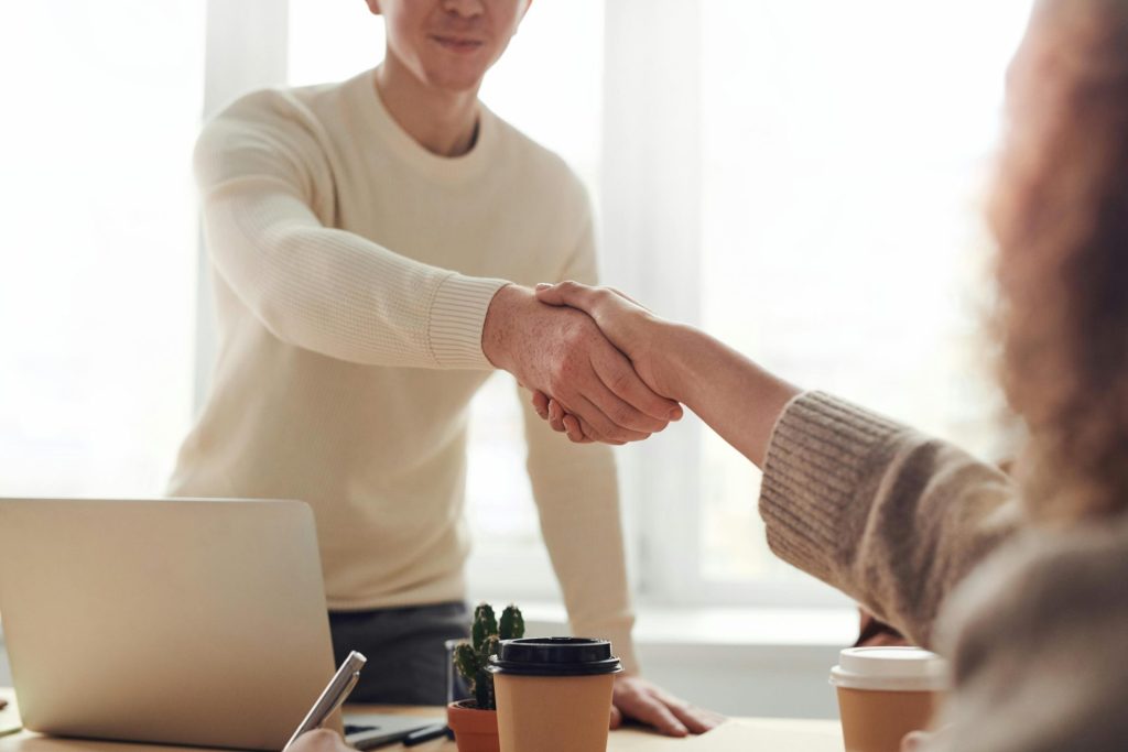 Gros plan sur des professionnels se serrant la main autour d'un café dans un bureau moderne.
